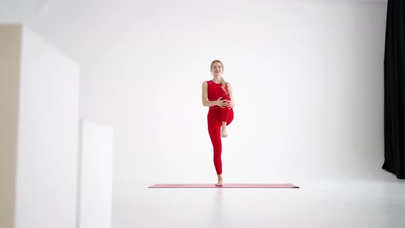 Beautiful Young Woman Wearing Red Sportswear Doing Yoga or Pilates Exercise Pose on White Background