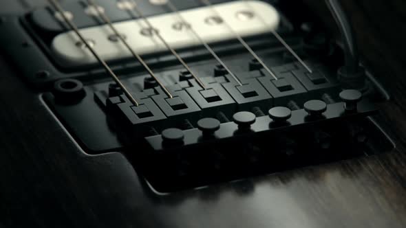 Electric guitar pickups and floyd-rose bridge details. Worn out, rusty strings.