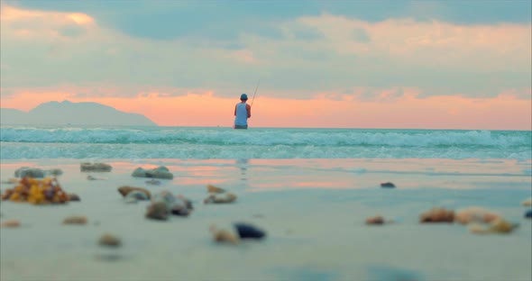 Beautiful Sunset in the Tropics on the Background of a Fisherman Who Fishes on Spinning in the Ocean