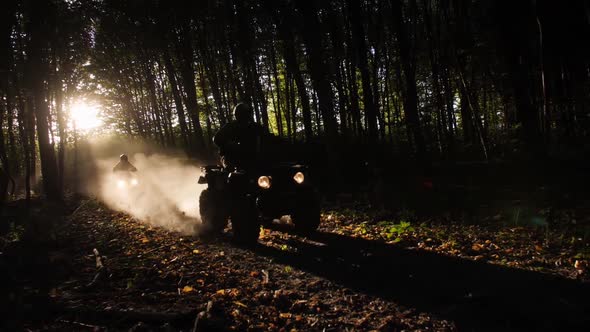 Two ATV Riders Ride Fast on a Forest Path