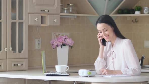 Attractive Brunette Businesswoman Talking in the Kitchen She Works As a Freelancer at Home