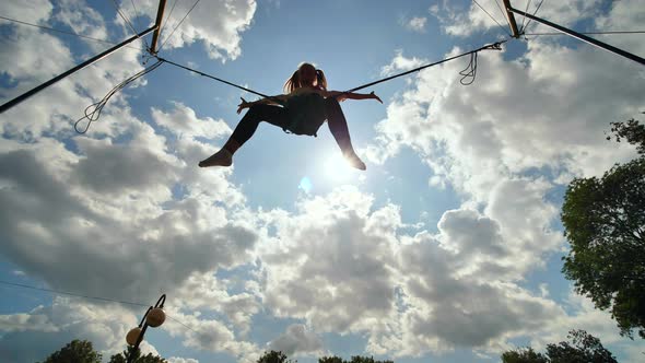 Teenage Girl Silhouette Jumping on the Trampoline Bungee Jumping. Slow Motion Video. alt