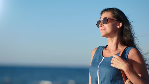 Happy Fashion Girl with Waving Hair Posing in Seascape Background at Sunset Medium Closeup