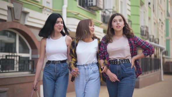 Portrait of Three Cheerful Happy Teenage Girls Walking in City Talking Smiling