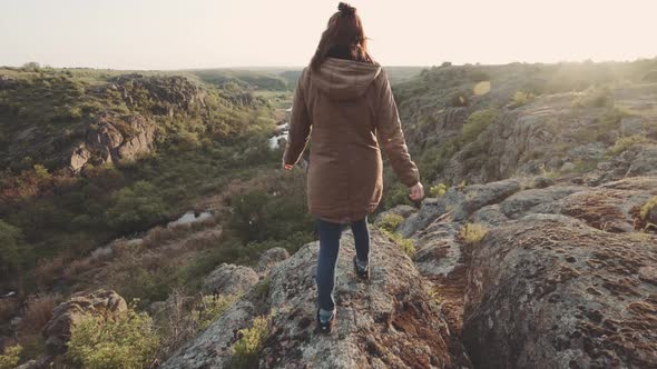 A Young Woman Traveler Walks in the Mountains at Canyon