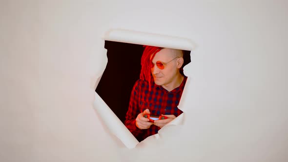 Young Man in Red Plaid Shirt with Gamepad and Playing Video Game