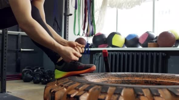 Sportswoman Hitting Tire with Sledge Hammer