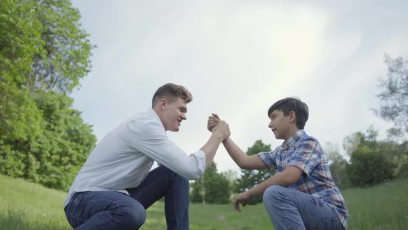 Young Father and the Boy High Five and Shaking Hands Outdoors. Father and a Kid Having Fun in the