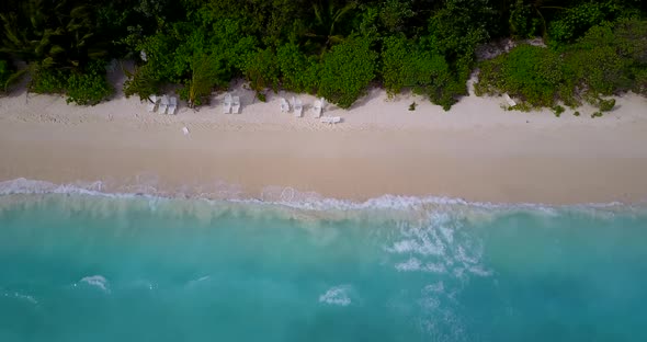Wide angle above clean view of a white sandy paradise beach and blue sea background in colorful 4K