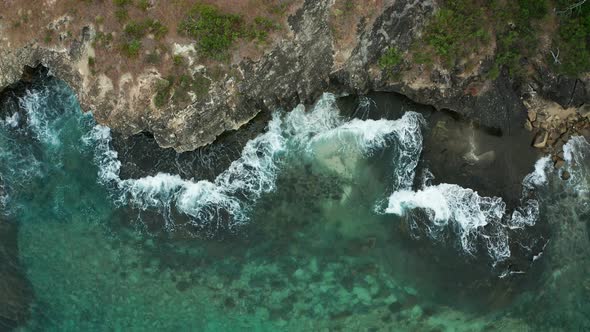 Emerald Water With The Waves Hitting The Shoreline And The Rough Edges Of The Rocks. -wide shot