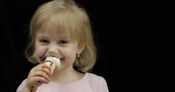 Child with Dirty Face Eats Banana with Melted Chocolate and Whipped Cream