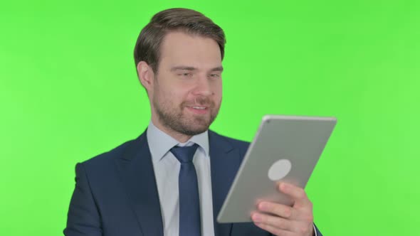 Video Call on Tablet by Young Businessman on Green Background
