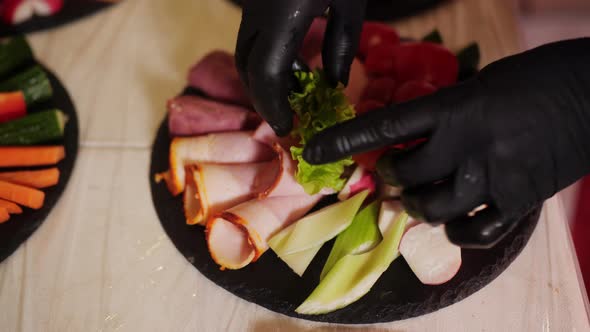 Close Up Hands of Cook Serving Meat Appetizer with Vegetables and Lettuce Salad for Dinner