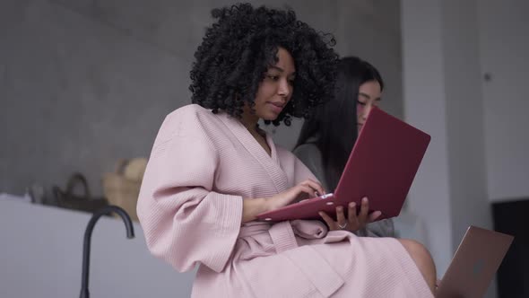 Side View of Confident Successful African American Woman Messaging Online with Blurred Asian