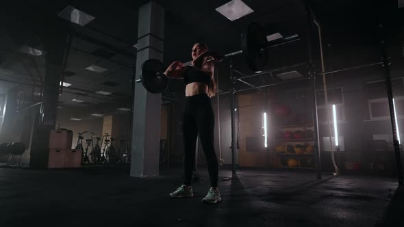 Athletic Beautiful Woman Does Overhead Deadlift with a Barbell in the Gym