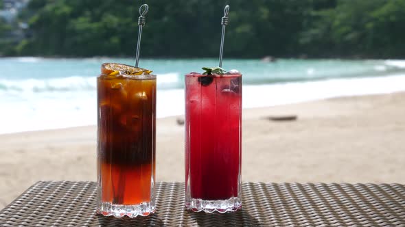 Beautiful Refreshing Fruit Cocktails on Table on Beach Blue Sea on Background