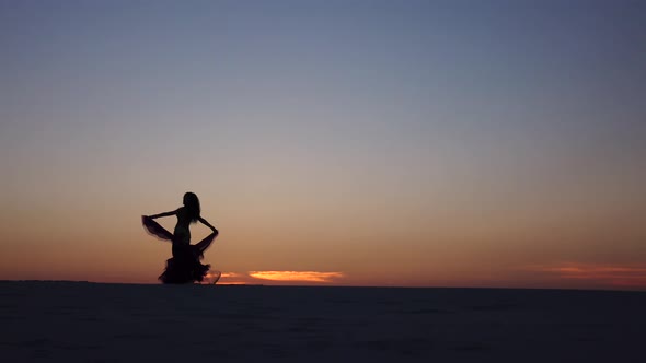 Girl Is Dancing Belly Dancing Against the Beautiful Sunset on the Beach, Silhouettes