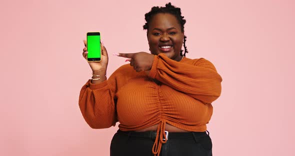 Black Model Holds Phone and Points Out on Gadget Screen