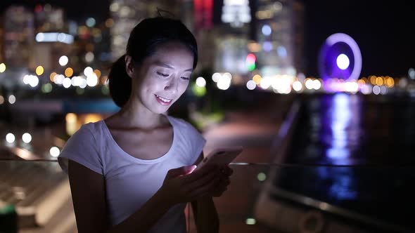 Woman sending text message on cellphone at night