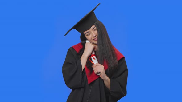 Portrait of Female Student in Cap and Gown Graduation Costume Holding Her Diploma and is Very Happy