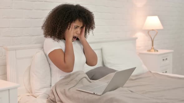 Young African Woman with Laptop Having Loss in Bed