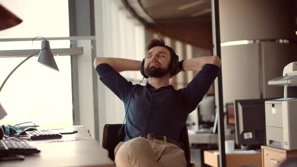 Healthy Stress Free Man Relaxing In Office And Listening To Music. Businessman Leisure In Headphone.