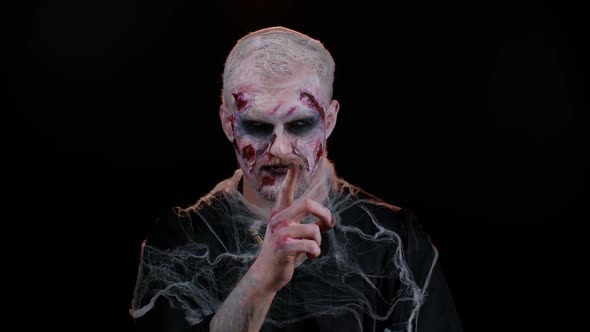 Halloween Zombie Man Presses Index Finger to Lips Makes Silence Gesture Sign Do Not Tells Secret