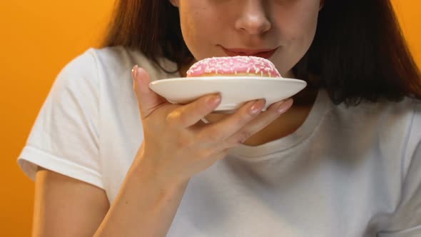 Satisfied Pretty Girl Showing Pink Glazed Donut Into Camera, Risk of Diabetes