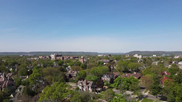 Pan over tree lined streets and diverse community neighborhood with blue sky and bluffs in distance.