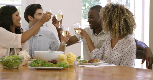 Two happy couple toasting wine glasses while having meal