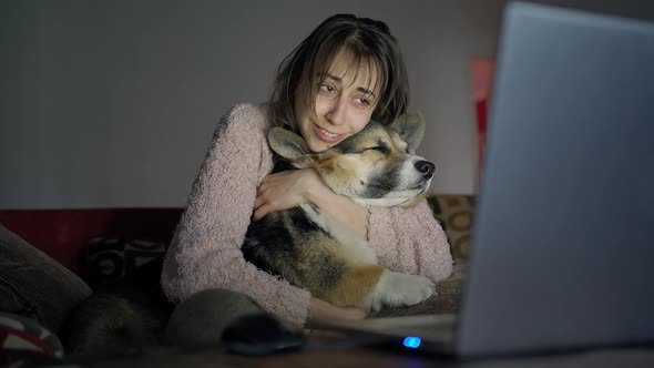 Affectionate Woman Sits on Couch with Dog and Watching Film