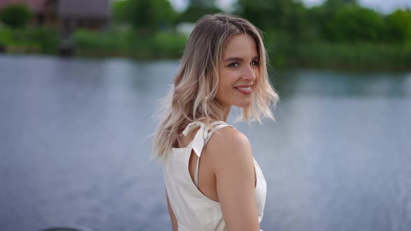 Back View Relaxed Happy Young Woman Standing on River Bank Turning Looking at Camera Smiling