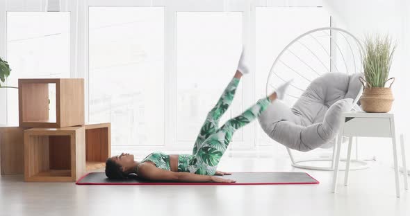 Black woman performing fitness exercises at home.