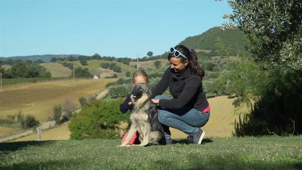 Little Girl with Mother Petting the Dog Outdoors