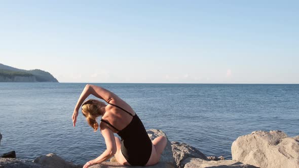 Young Woman in Black Swimsuit Doing Stretching Exercises at Seashore