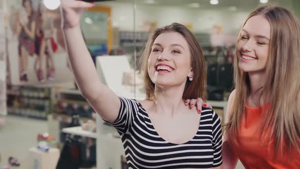 Beautiful Girls with Shopping Bags Taking a "Selfie" with Their Cell Phone