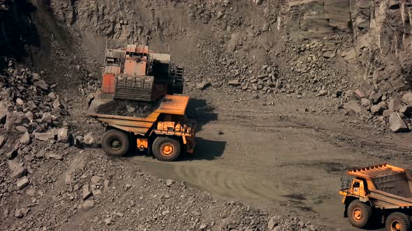 Iron ore mining. Big yellow dump trucks and excavator in the quarry.