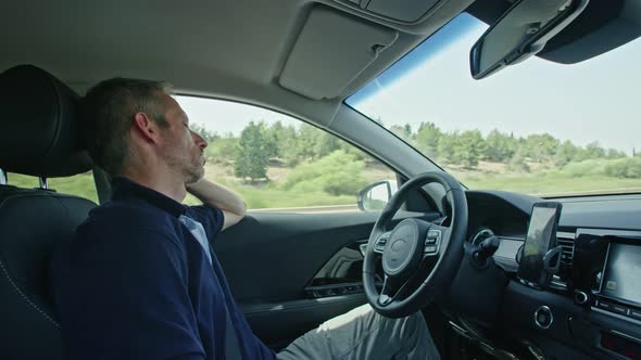 Male driver sitting in an autonomous car, letting the car drive by itself