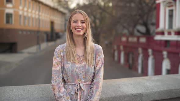 Portrait of Excited Young Woman 20s in Beautiful Dress Laughing While Walking Outdoor with Cars and