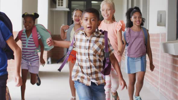 Video of happy diverse pupils running on school corridor