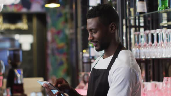 African american barista using tablet smiling in cafe