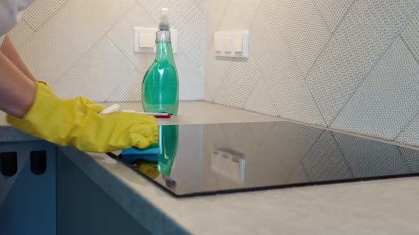 Woman Cleaning Induction Hob in Kitchen