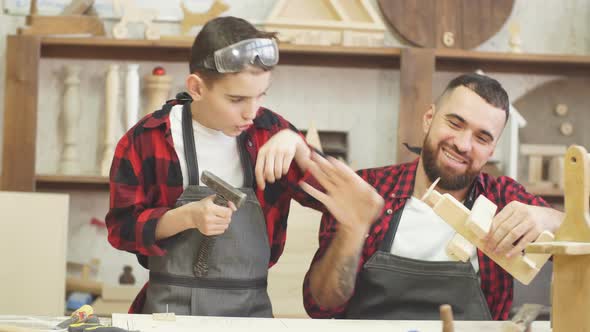 Carpenter Building a Wooden Airplan Together with His Kid