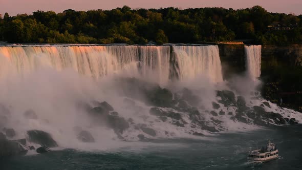 Maid of the mist travels near the roaring falls on the Canadian side of Niagara at sunset.