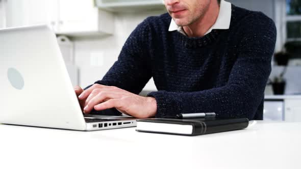 Man using laptop in the kitchen