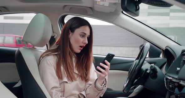 Surprised Woman Getting Good News on Mobile Phone Sitting in Car