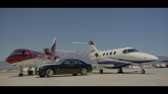 Black Rolls Royce  with private jets at the airport