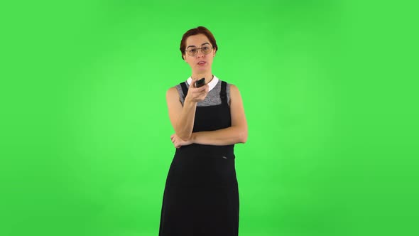 Funny Girl in Round Glasses with TV Remote in Her Hand, Switching on TV. Green Screen