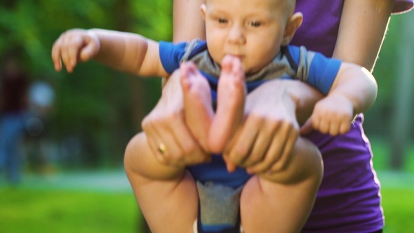 Woman holding baby and doing exercises in park