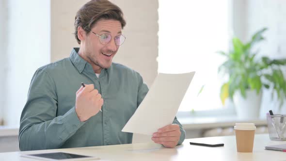 Middle Aged Man Celebrating Success on Documents